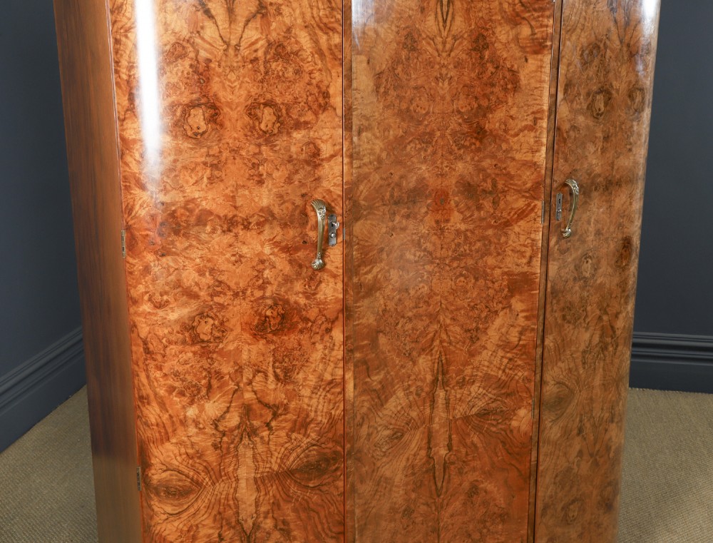 An English Art Deco triple-door wardrobe crafted from figured burr walnut with curved sides and vertical handles. View III