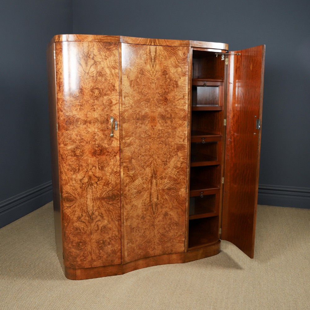 An English Art Deco triple-door wardrobe crafted from figured burr walnut with curved sides and vertical handles. View VI