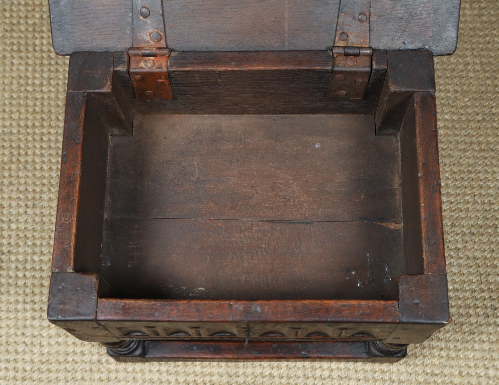 A small antique dark oak box stool featuring a hinged top lid, hand-carved frieze panels, turned legs, and square perimeter stretchers. View VIII