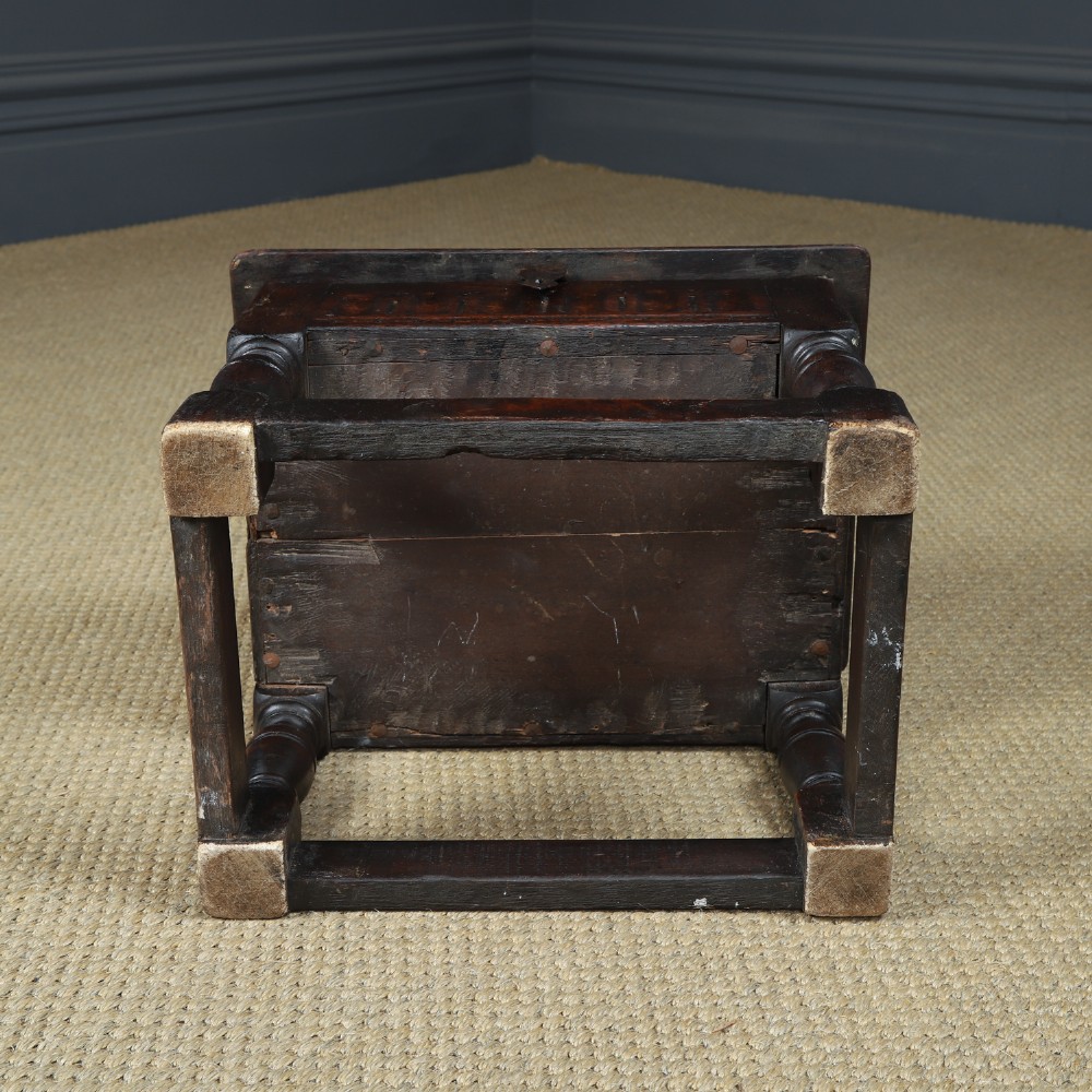 A small antique dark oak box stool featuring a hinged top lid, hand-carved frieze panels, turned legs, and square perimeter stretchers. View XIV