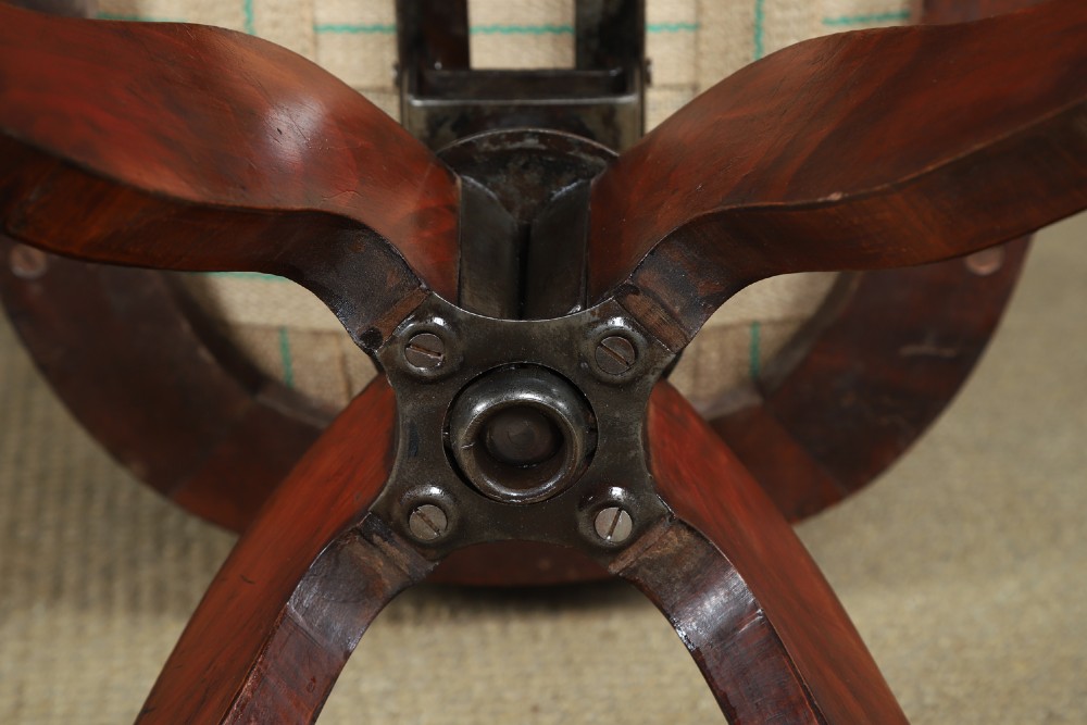An antique George V stained beech revolving office chair featuring a slatted backrest, green leather seat, and splayed legs on brass castors. View XII