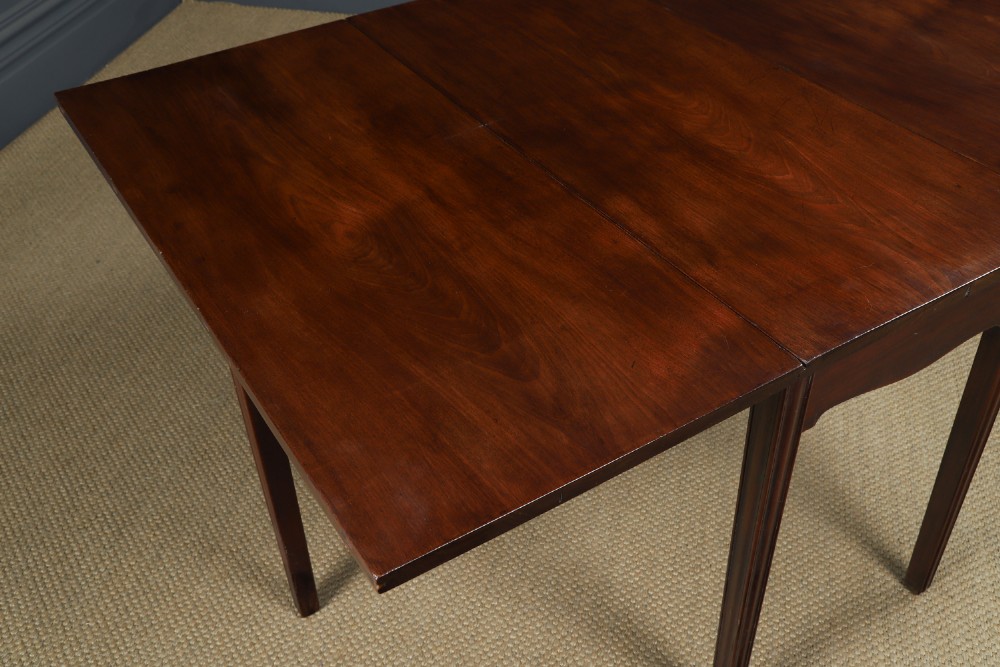 A Georgian mahogany drop-leaf dining table shown fully extended with rectangular flaps, a shaped apron, and straight square legs. View IV