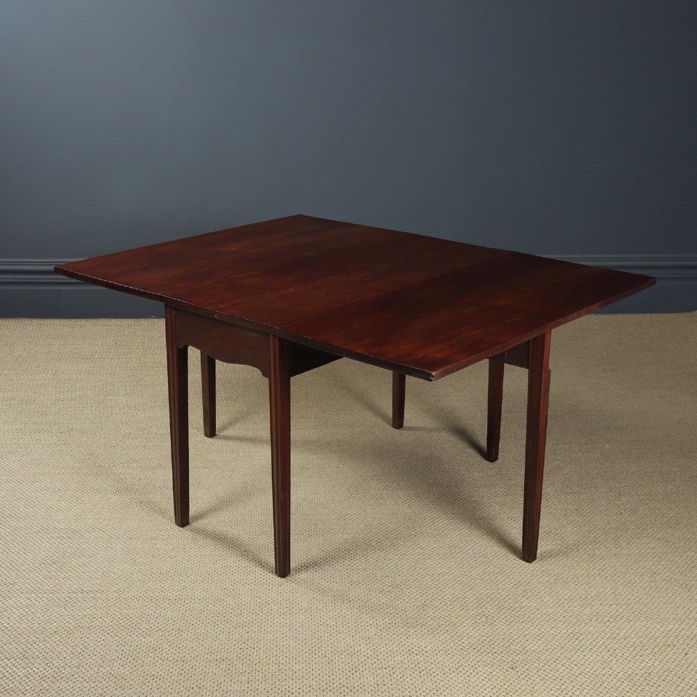 A Georgian mahogany drop-leaf dining table shown fully extended with rectangular flaps, a shaped apron, and straight square legs. View V
