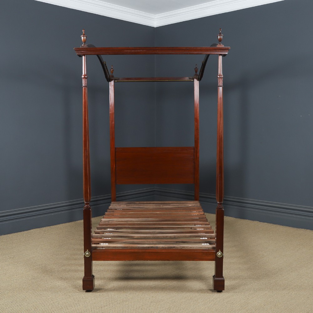 An Edwardian mahogany single four poster bed with turned posts, an arched canopy structure, and neutral drapery. View II