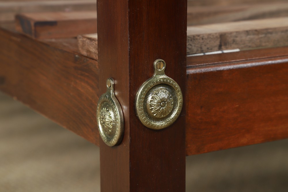 An Edwardian mahogany single four poster bed with turned posts, an arched canopy structure, and neutral drapery. View V