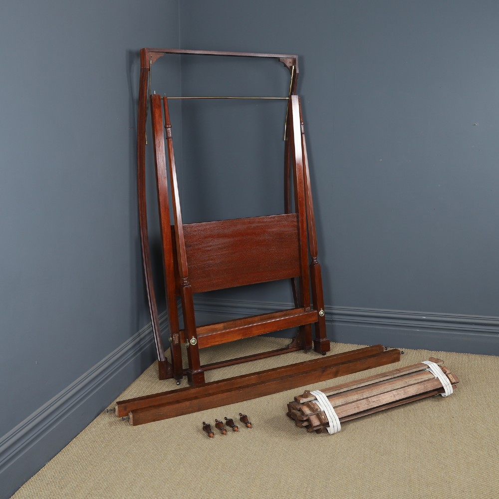 An Edwardian mahogany single four poster bed with turned posts, an arched canopy structure, and neutral drapery. View XV
