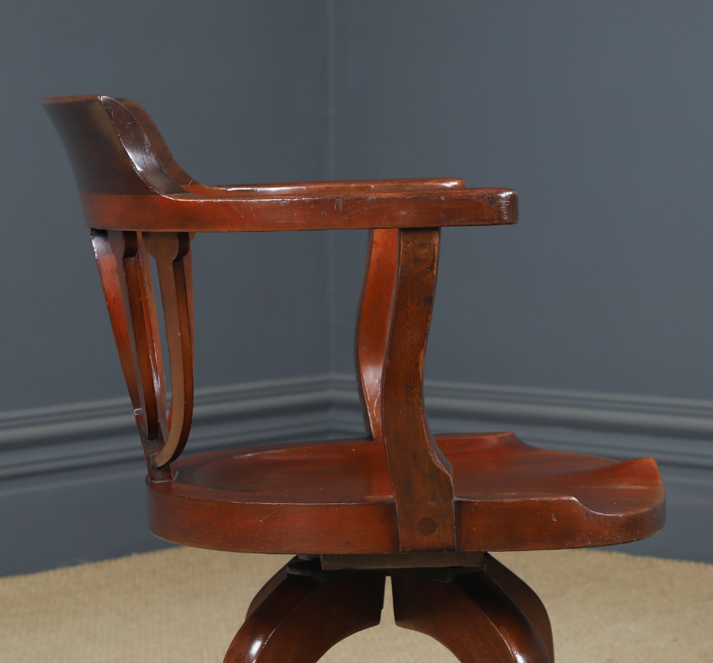 Victorian mahogany revolving desk armchair featuring a curved crest rail, pierced splat back, contoured wooden seat, and four legs with castors. View VI