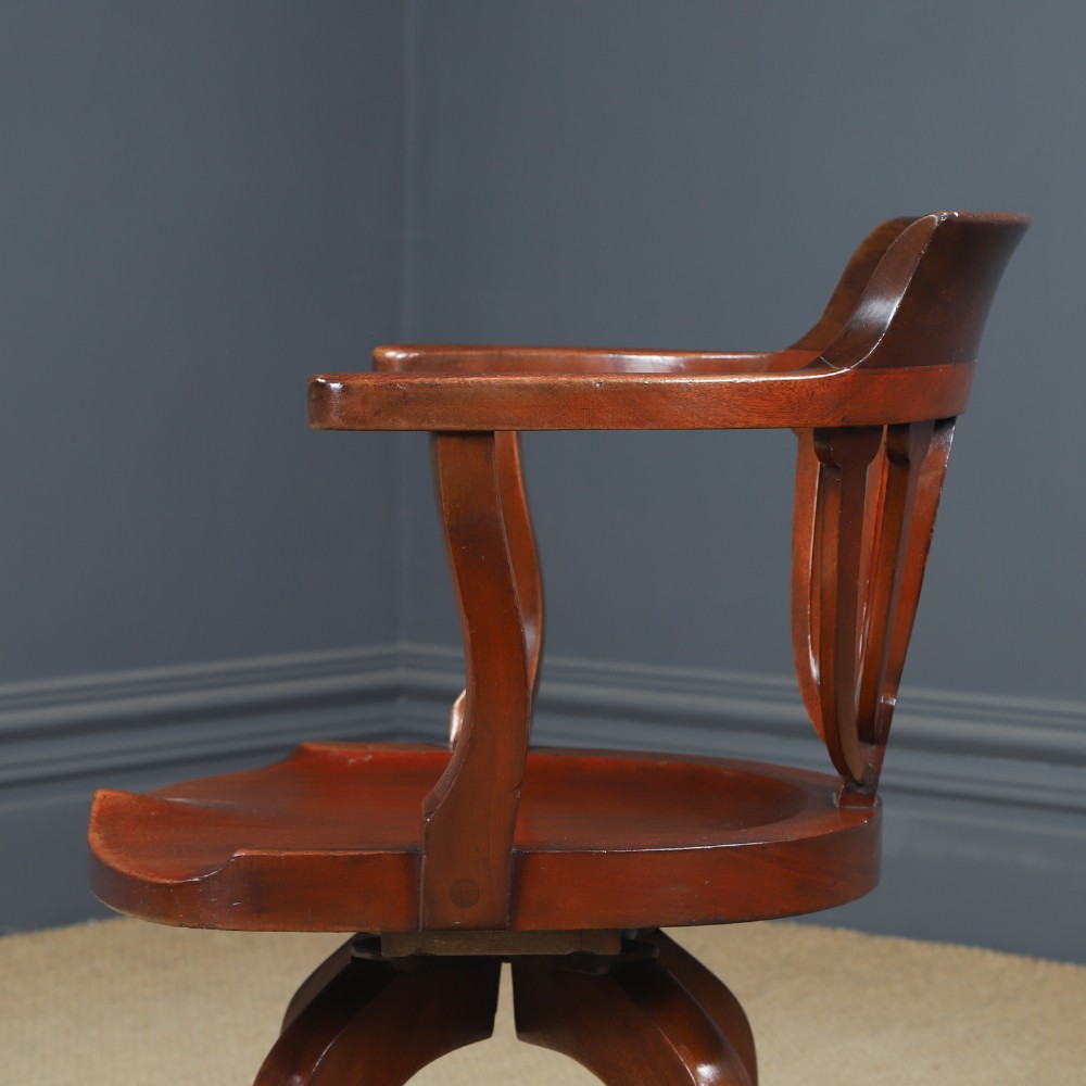 Victorian mahogany revolving desk armchair featuring a curved crest rail, pierced splat back, contoured wooden seat, and four legs with castors. View VII