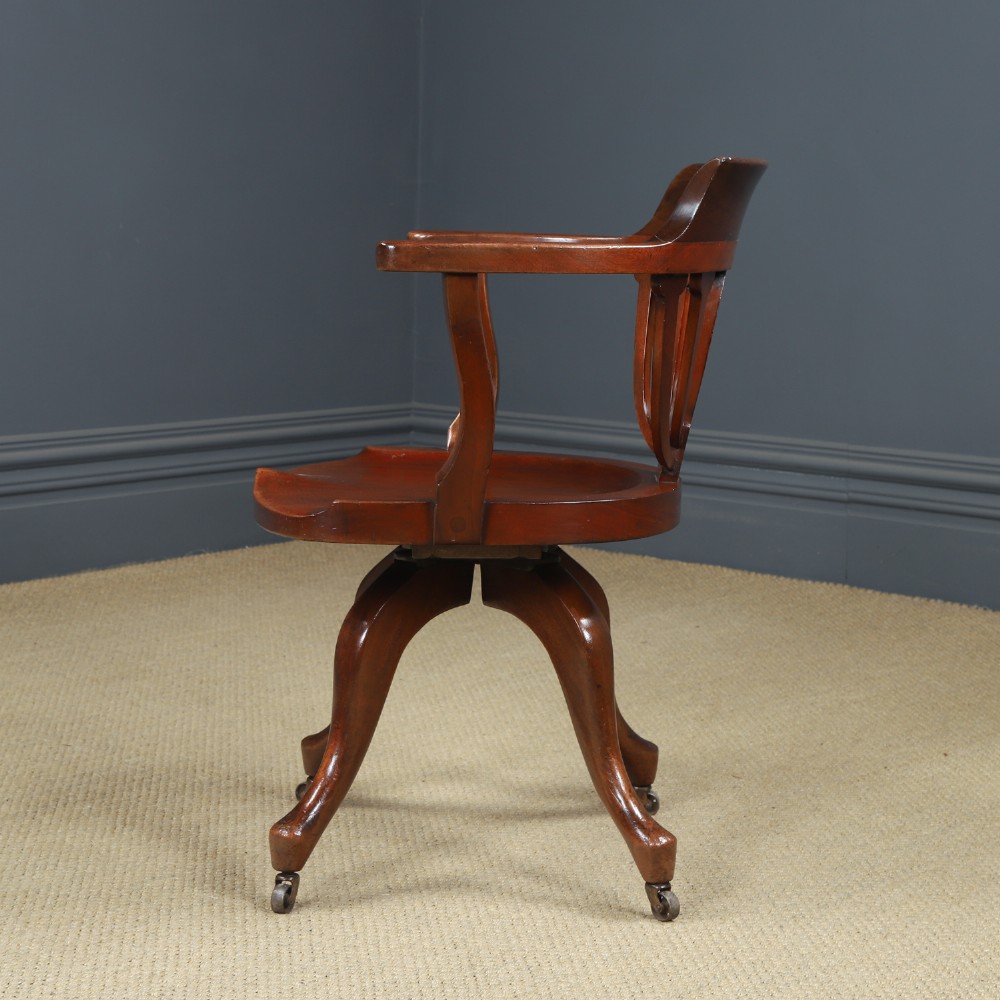 Victorian mahogany revolving desk armchair featuring a curved crest rail, pierced splat back, contoured wooden seat, and four legs with castors. View VIII