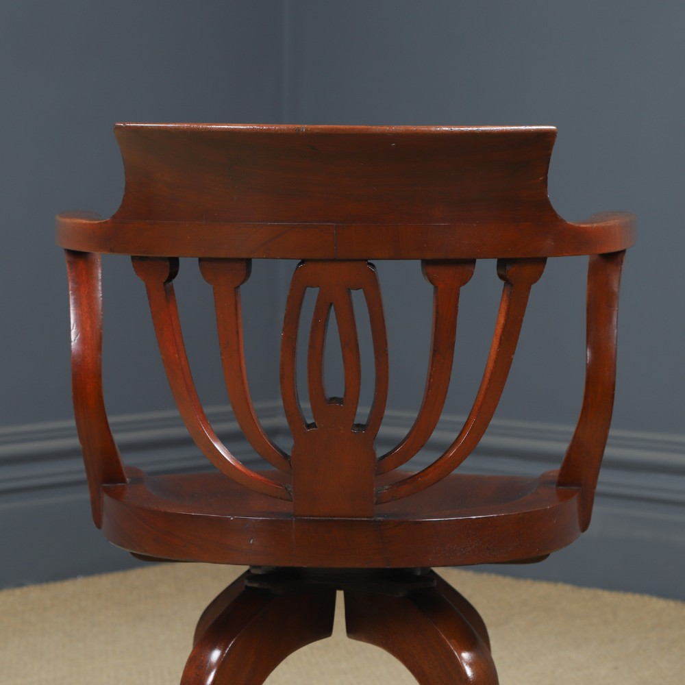 Victorian mahogany revolving desk armchair featuring a curved crest rail, pierced splat back, contoured wooden seat, and four legs with castors. View IX