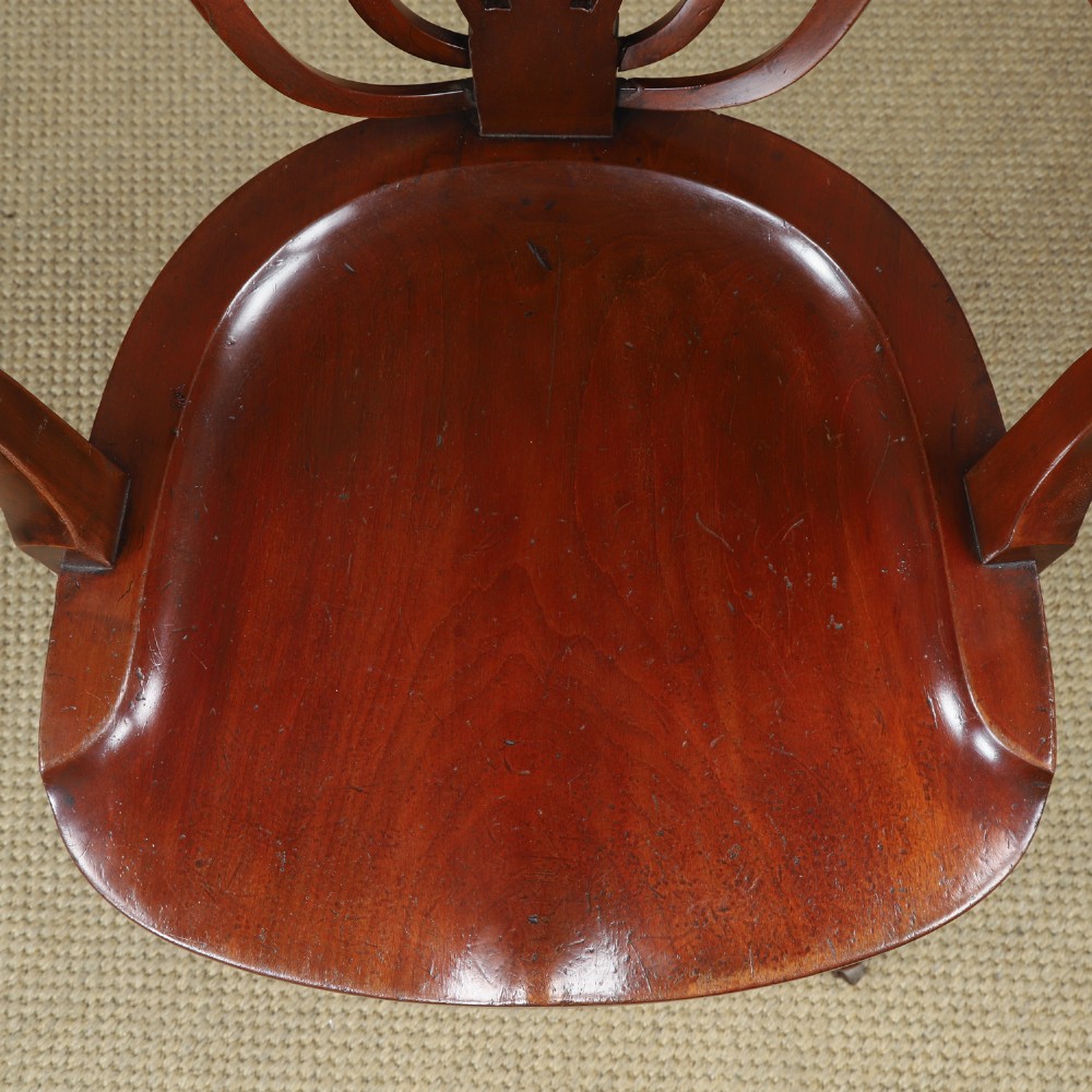 Victorian mahogany revolving desk armchair featuring a curved crest rail, pierced splat back, contoured wooden seat, and four legs with castors. View XII
