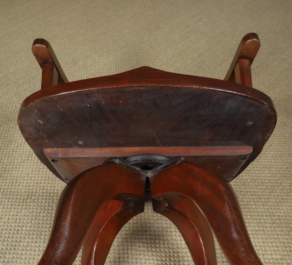 Victorian mahogany revolving desk armchair featuring a curved crest rail, pierced splat back, contoured wooden seat, and four legs with castors. View XIV