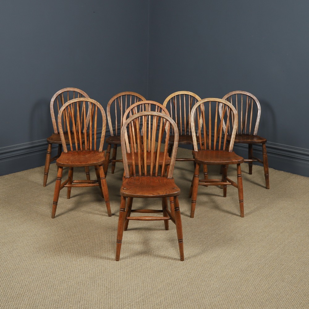 A set of eight antique Edwardian ash and elm Windsor dining chairs with arched hoop stick backs, shaped seats, and turned legs.