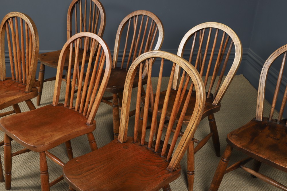 A set of eight antique Edwardian ash and elm Windsor dining chairs with arched hoop stick backs, shaped seats, and turned legs. View V
