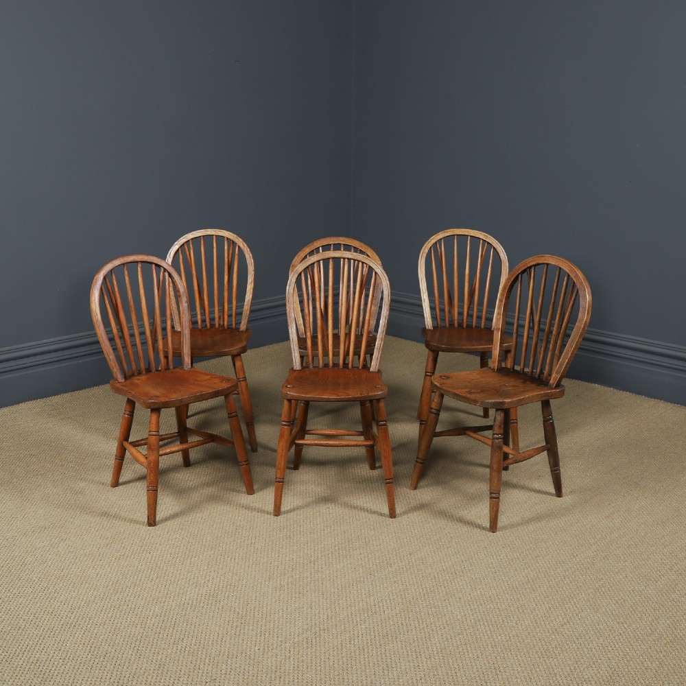 A set of six Edwardian Windsor dining chairs crafted from ash and elm wood, featuring hoop-and-stick backs, shaped seats, turned legs, and H-stretchers.