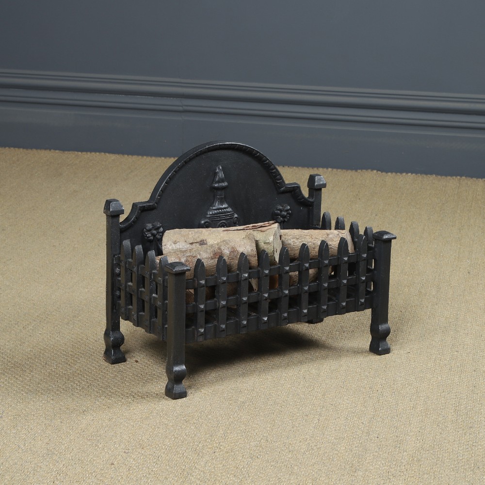 A black cast iron open fire grate featuring an arched backplate decorated with an urn relief and a palisade front basket resting on four square legs.