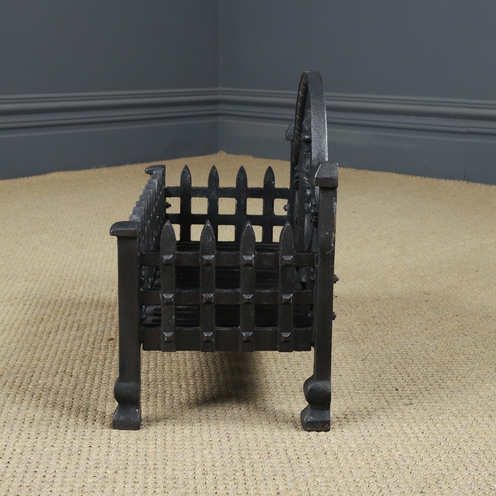 A black cast iron open fire grate featuring an arched backplate decorated with an urn relief and a palisade front basket resting on four square legs. View XI
