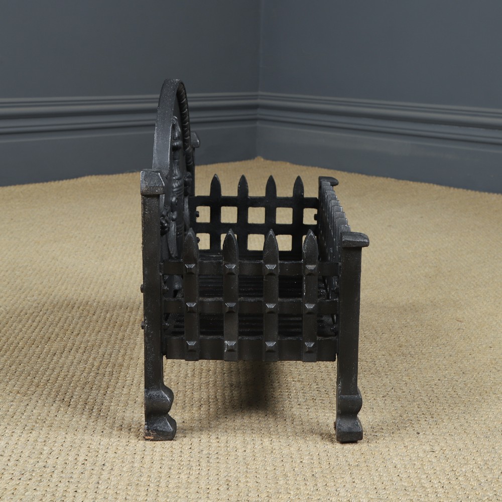 A black cast iron open fire grate featuring an arched backplate decorated with an urn relief and a palisade front basket resting on four square legs. View XII