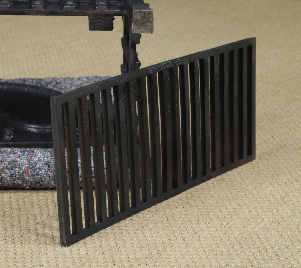 A black cast iron open fire grate featuring an arched backplate decorated with an urn relief and a palisade front basket resting on four square legs. View XV