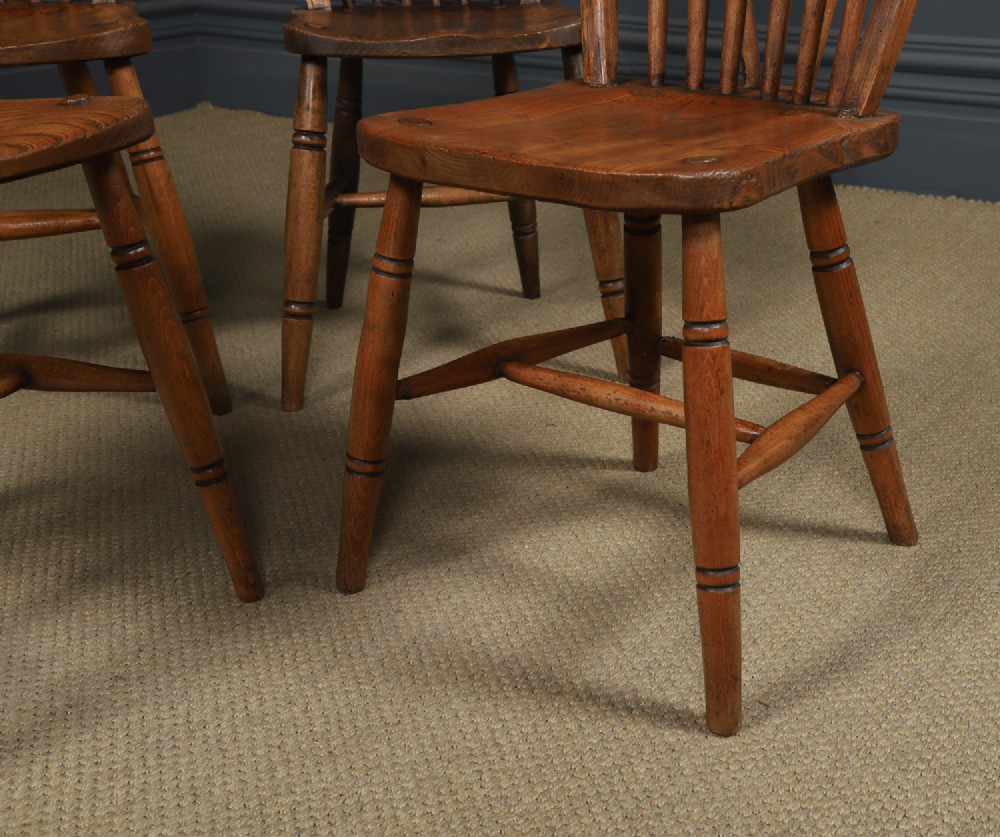 A set of four antique English warm brown ash and elm Windsor dining chairs featuring hoop backs, stick spindles, and turned legs. View II