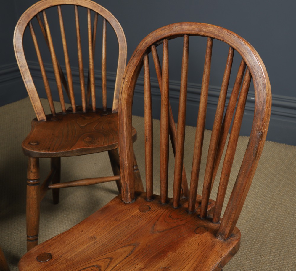 A set of four antique English warm brown ash and elm Windsor dining chairs featuring hoop backs, stick spindles, and turned legs. View V