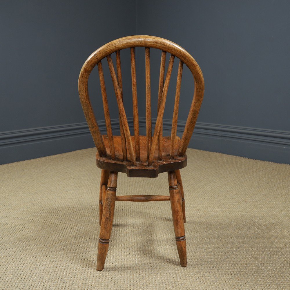 A set of four antique English warm brown ash and elm Windsor dining chairs featuring hoop backs, stick spindles, and turned legs. View X