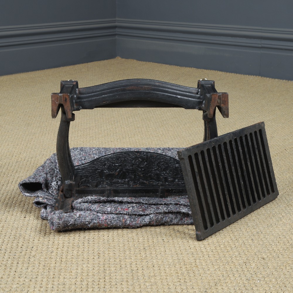 A black cast iron fire grate featuring an arched pictorial backplate, curved front bars, and brass urn finials on the front posts. View XV
