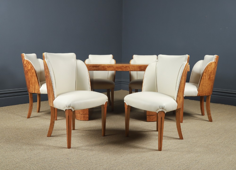 An English Art Deco dining suite featuring a rectangular satinwood and maple dining table with a glass top and six cream leather upholstered chairs with curved veneered backs. View II