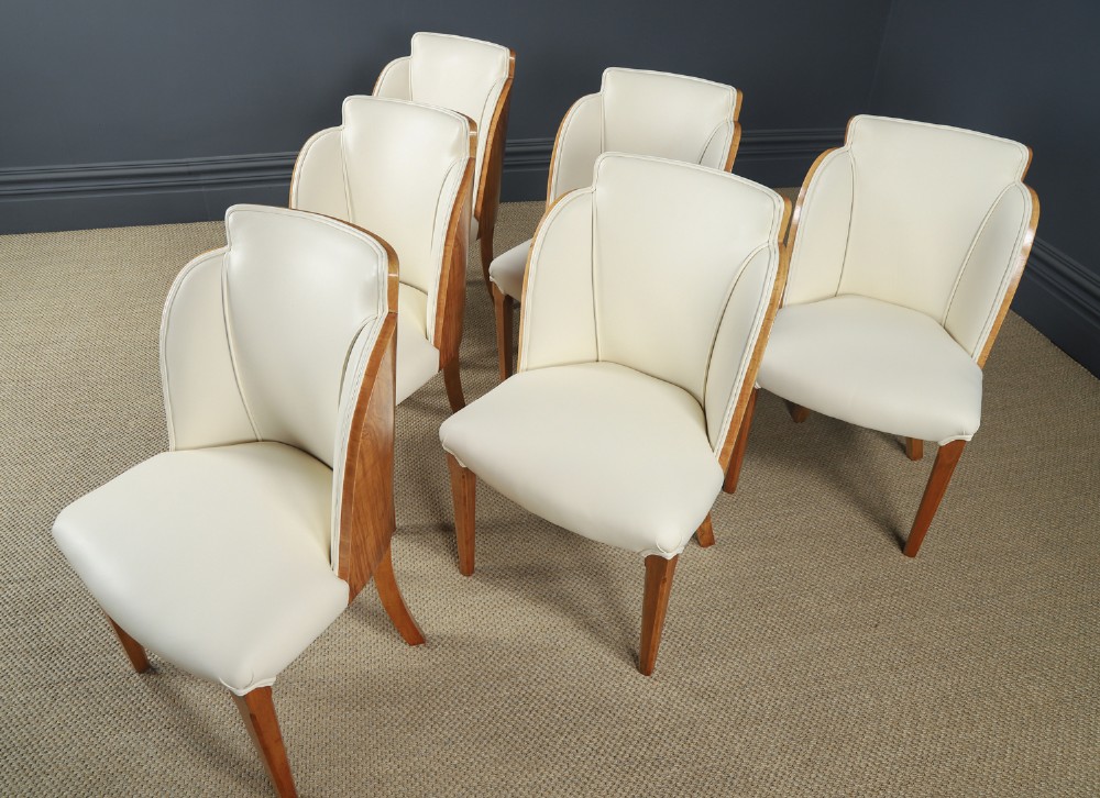 An English Art Deco dining suite featuring a rectangular satinwood and maple dining table with a glass top and six cream leather upholstered chairs with curved veneered backs. View III