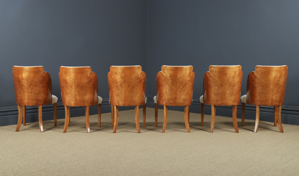 An English Art Deco dining suite featuring a rectangular satinwood and maple dining table with a glass top and six cream leather upholstered chairs with curved veneered backs. View VI