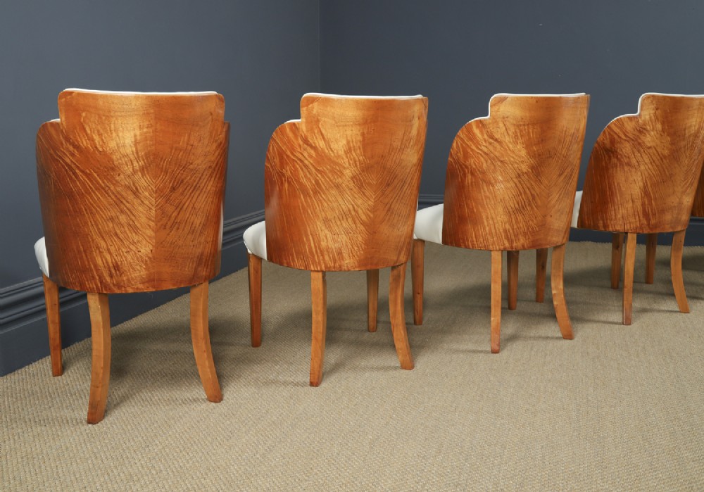 An English Art Deco dining suite featuring a rectangular satinwood and maple dining table with a glass top and six cream leather upholstered chairs with curved veneered backs. View VII