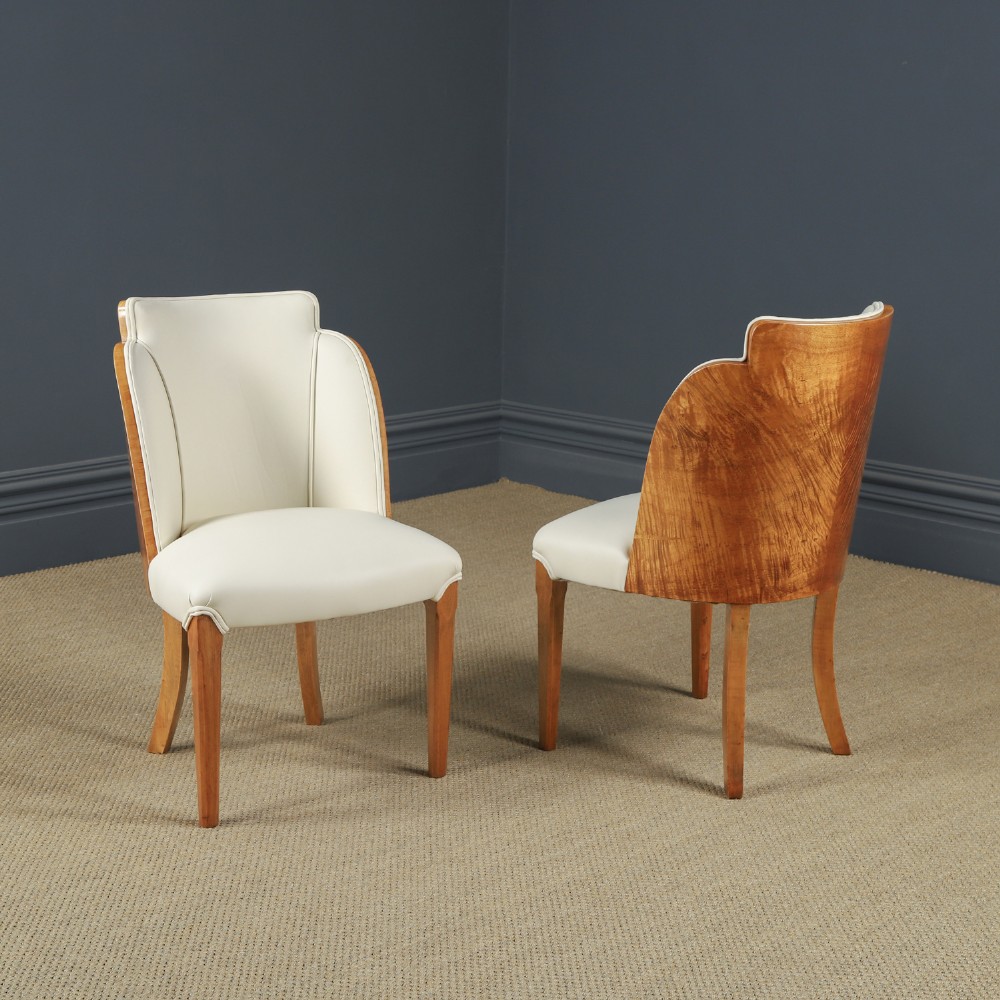 An English Art Deco dining suite featuring a rectangular satinwood and maple dining table with a glass top and six cream leather upholstered chairs with curved veneered backs. View VIII
