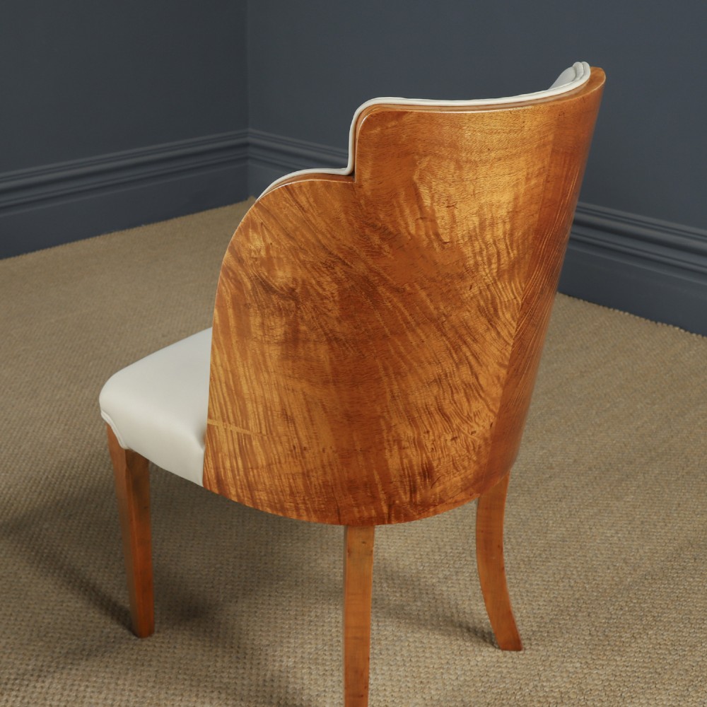 An English Art Deco dining suite featuring a rectangular satinwood and maple dining table with a glass top and six cream leather upholstered chairs with curved veneered backs. View X