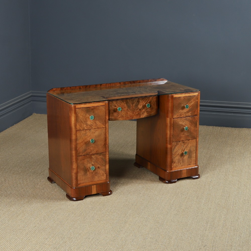 An Art Deco burr walnut pedestal writing desk with green circular knobs and a fitted glass top.