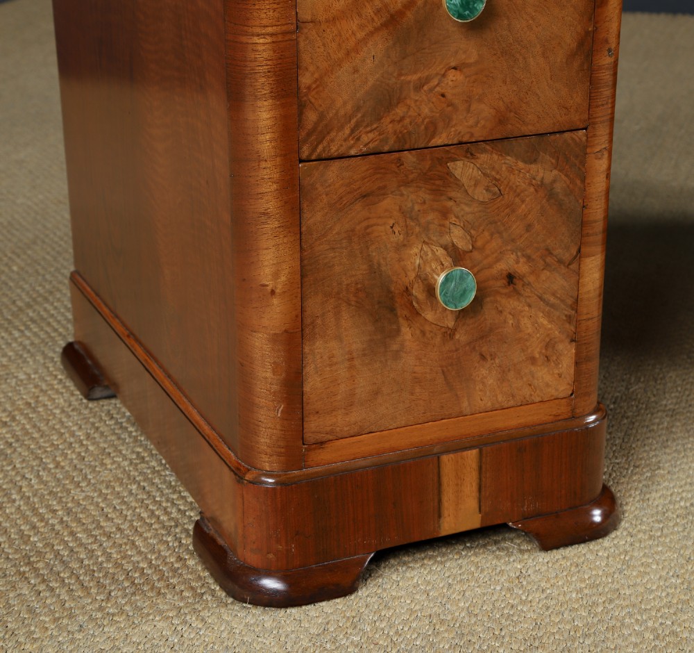 An Art Deco burr walnut pedestal writing desk with green circular knobs and a fitted glass top. View II