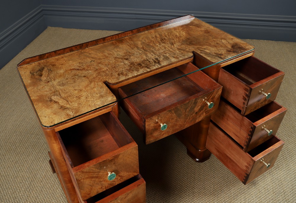 An Art Deco burr walnut pedestal writing desk with green circular knobs and a fitted glass top. View X