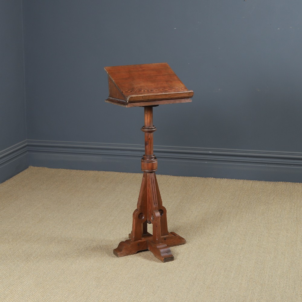 An antique Victorian pitch pine lectern featuring a slanted book rest, turned central column, and a Gothic-style pedestal base.