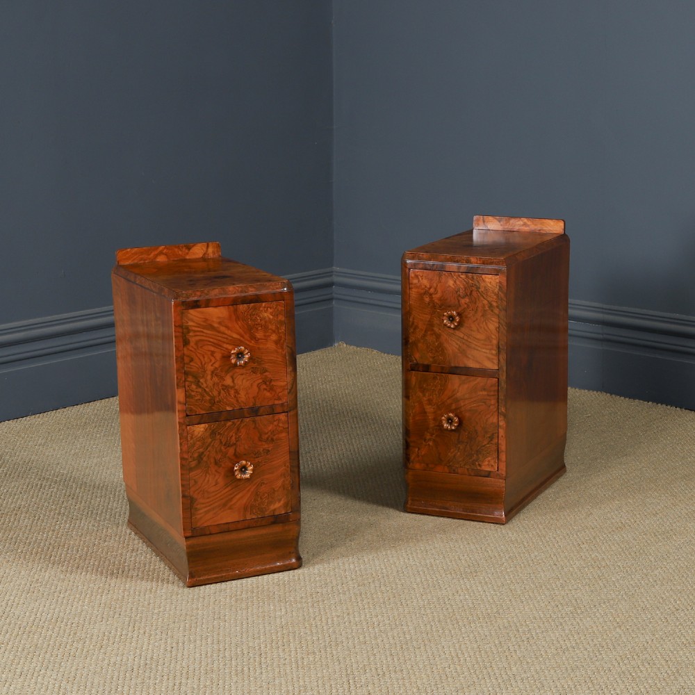A pair of narrow Art Deco burr walnut bedside cabinets featuring two drawers with carved circular handles and a low back ledge.
