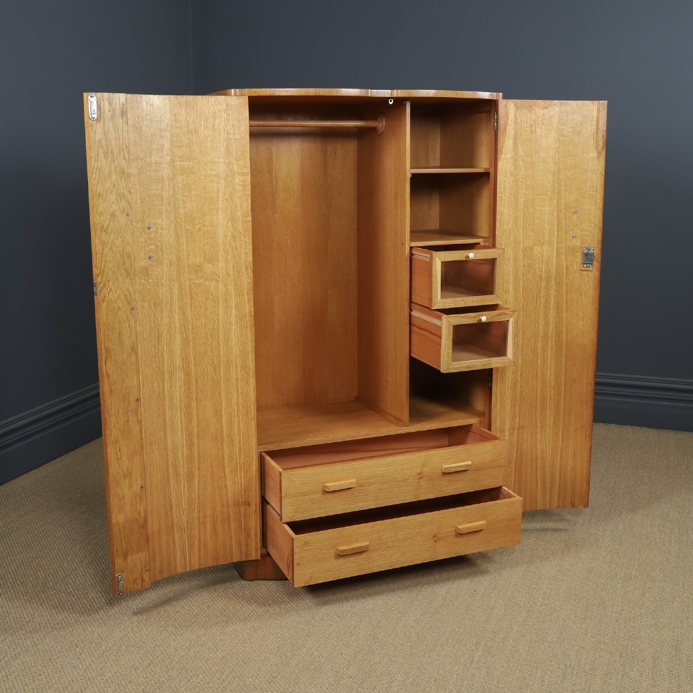 An Art Deco walnut two door wardrobe featuring a bow front design, carved wood handles, and figured timber grain. View VIII