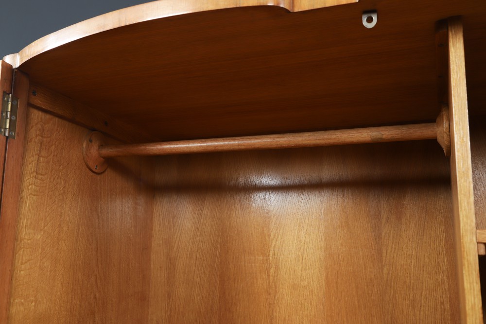 An Art Deco walnut two door wardrobe featuring a bow front design, carved wood handles, and figured timber grain. View XI