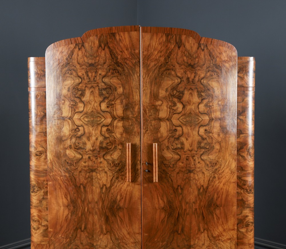 An Art Deco two door wardrobe crafted from warm brown figured walnut veneer with a gently curved bow front and wooden vertical handles. View II