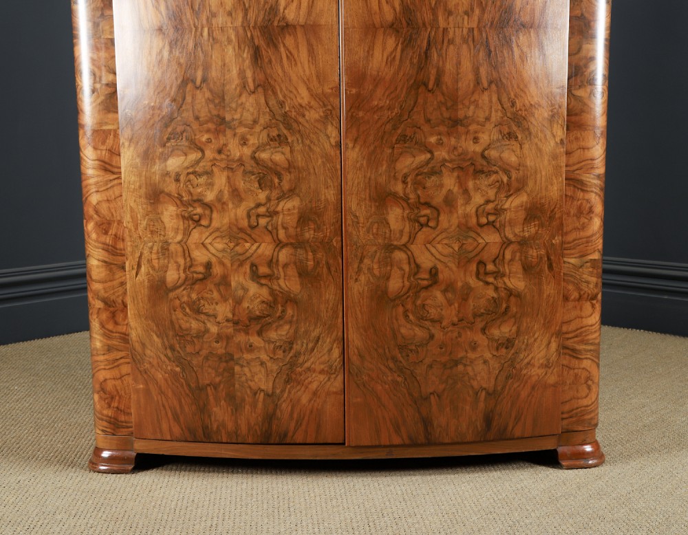 An Art Deco two door wardrobe crafted from warm brown figured walnut veneer with a gently curved bow front and wooden vertical handles. View III