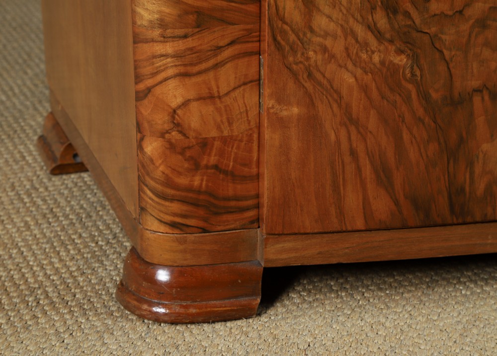 An Art Deco two door wardrobe crafted from warm brown figured walnut veneer with a gently curved bow front and wooden vertical handles. View IV