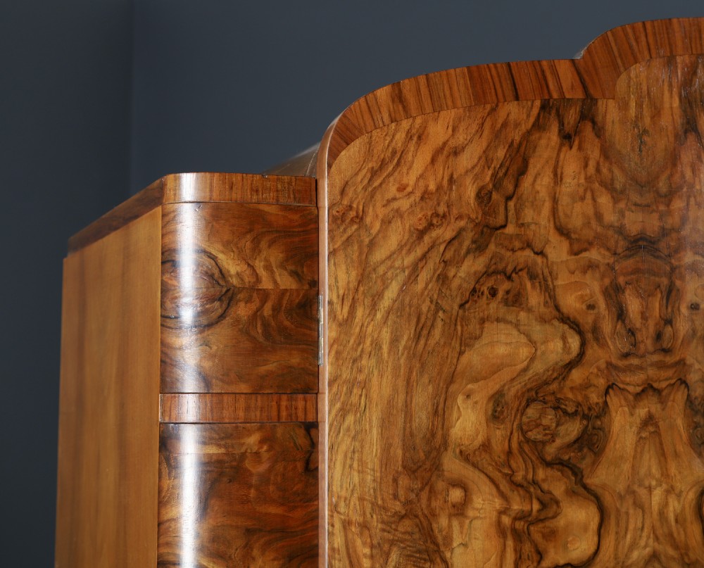 An Art Deco two door wardrobe crafted from warm brown figured walnut veneer with a gently curved bow front and wooden vertical handles. View VII