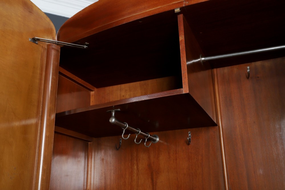 An Art Deco two door wardrobe crafted from warm brown figured walnut veneer with a gently curved bow front and wooden vertical handles. View X