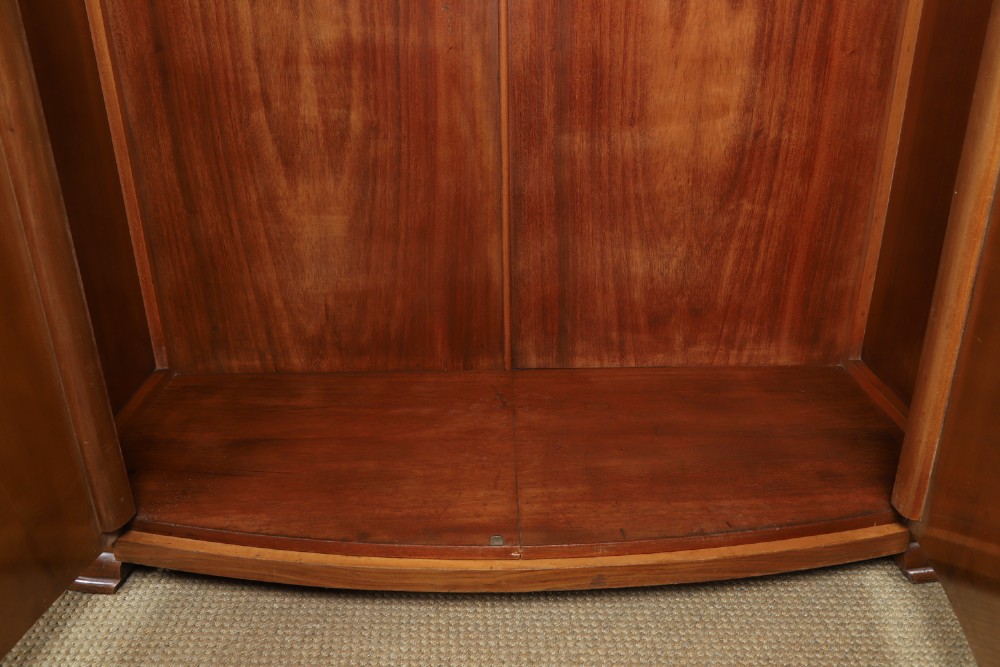 An Art Deco two door wardrobe crafted from warm brown figured walnut veneer with a gently curved bow front and wooden vertical handles. View XI