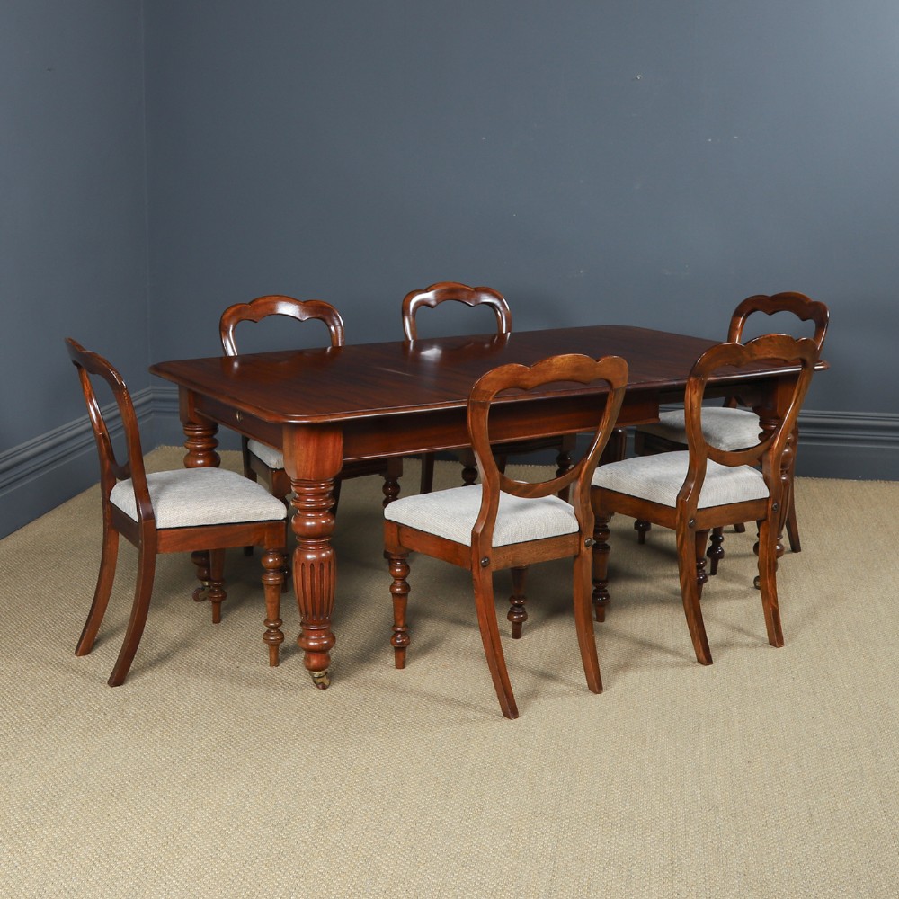 A Victorian mahogany extending dining table with a rectangular top, rounded corners, and turned fluted legs set on brass castors. View II