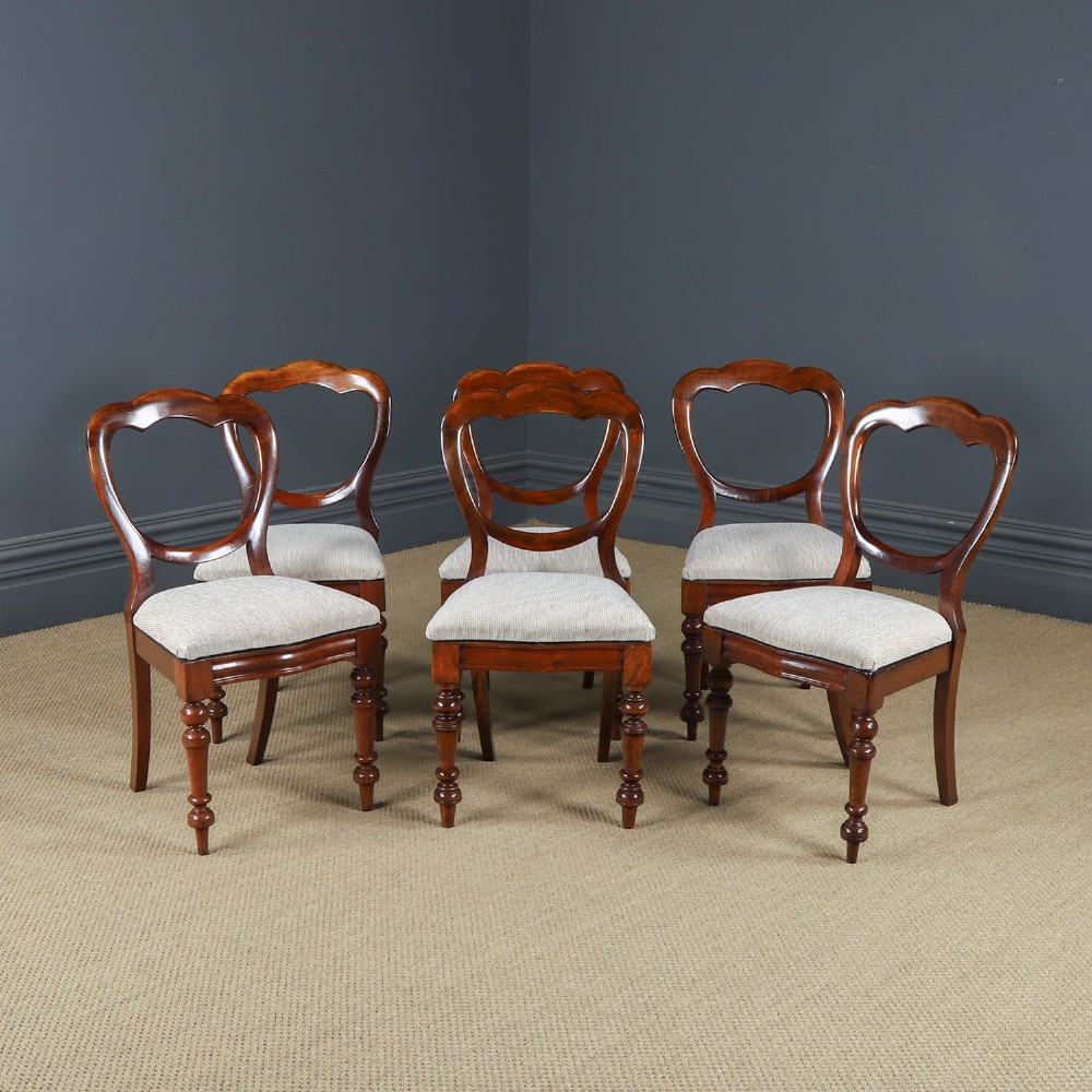 A set of six Victorian mahogany dining chairs featuring open balloon-shaped backs, turned front legs, and neutral upholstered seats.