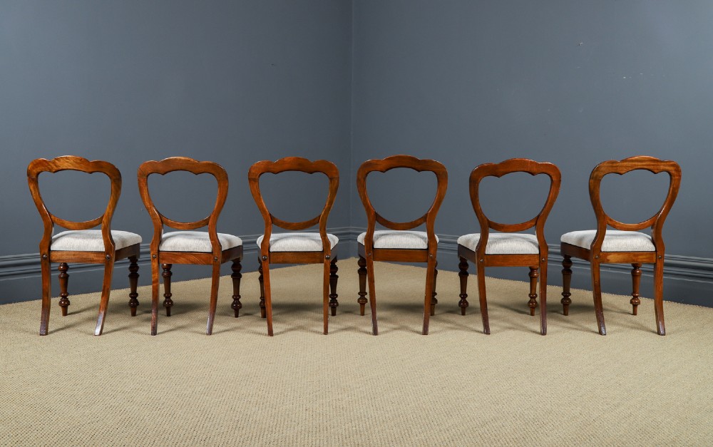A set of six Victorian mahogany dining chairs featuring open balloon-shaped backs, turned front legs, and neutral upholstered seats. View XV
