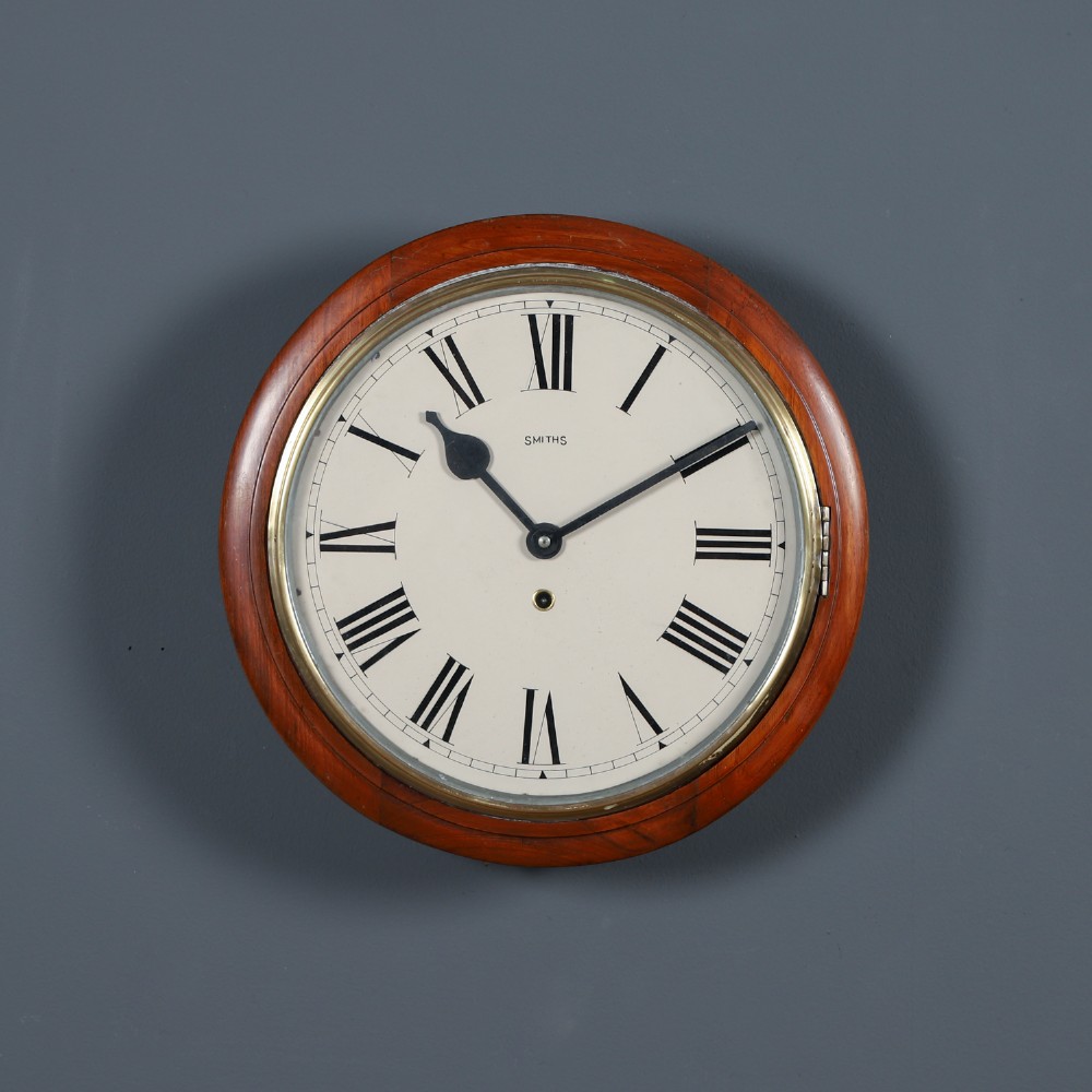 An antique Smiths circular wall clock with a turned mahogany surround, off-white dial plate, black Roman numerals, and brass bezel.